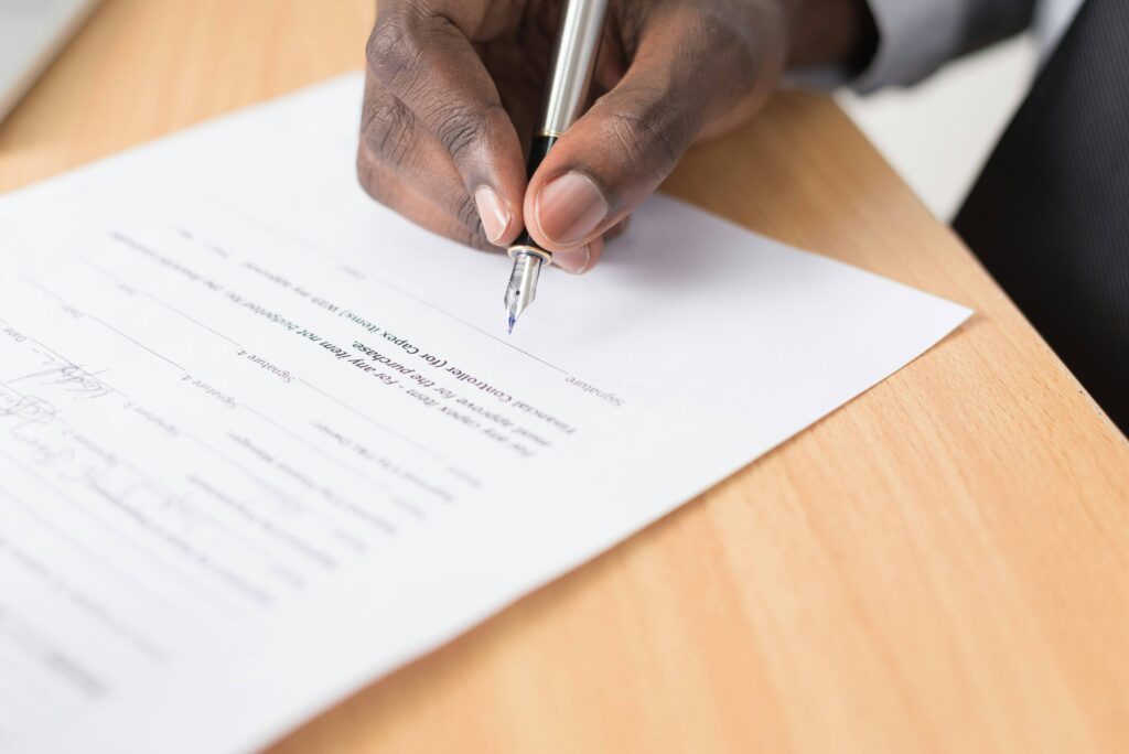 a hand holding a pen, poised to sign financing documents