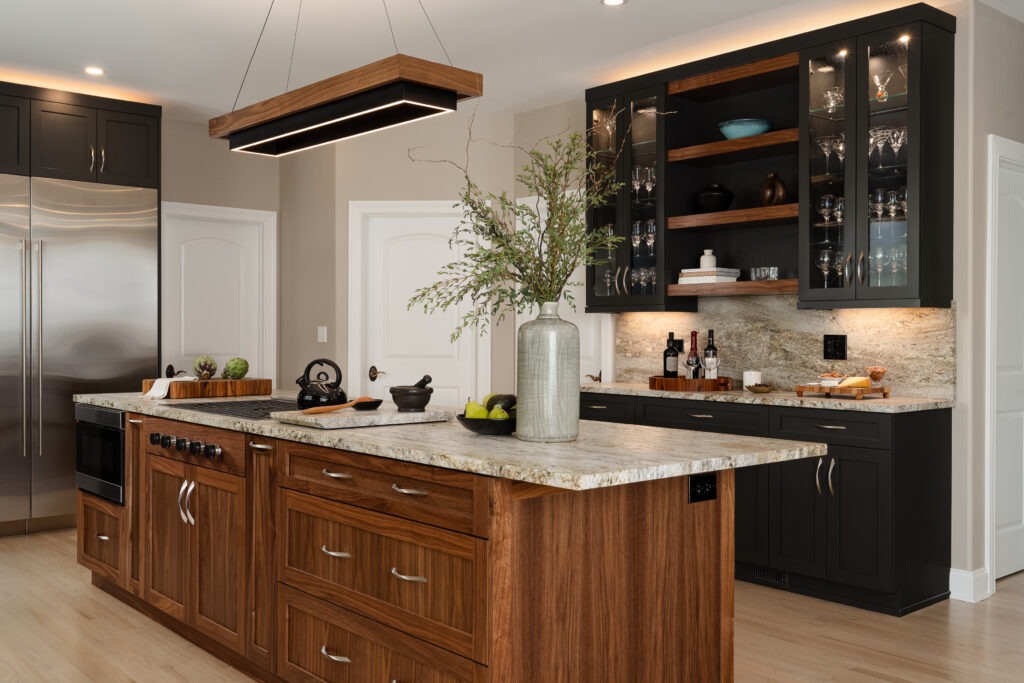 Large Kitchen Island with warn walnut cabinets and Blue Dunes granite in front of an Iron Ore dry bar